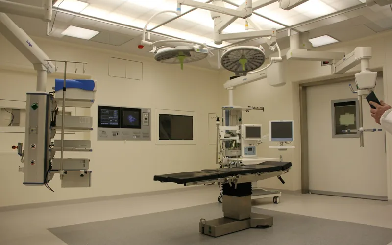 A bright, empty operating room with an operating table, surgical lights and monitors.